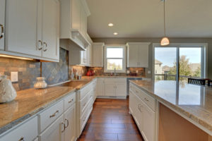 Bright kitchen with white cabinets and wooden floor.